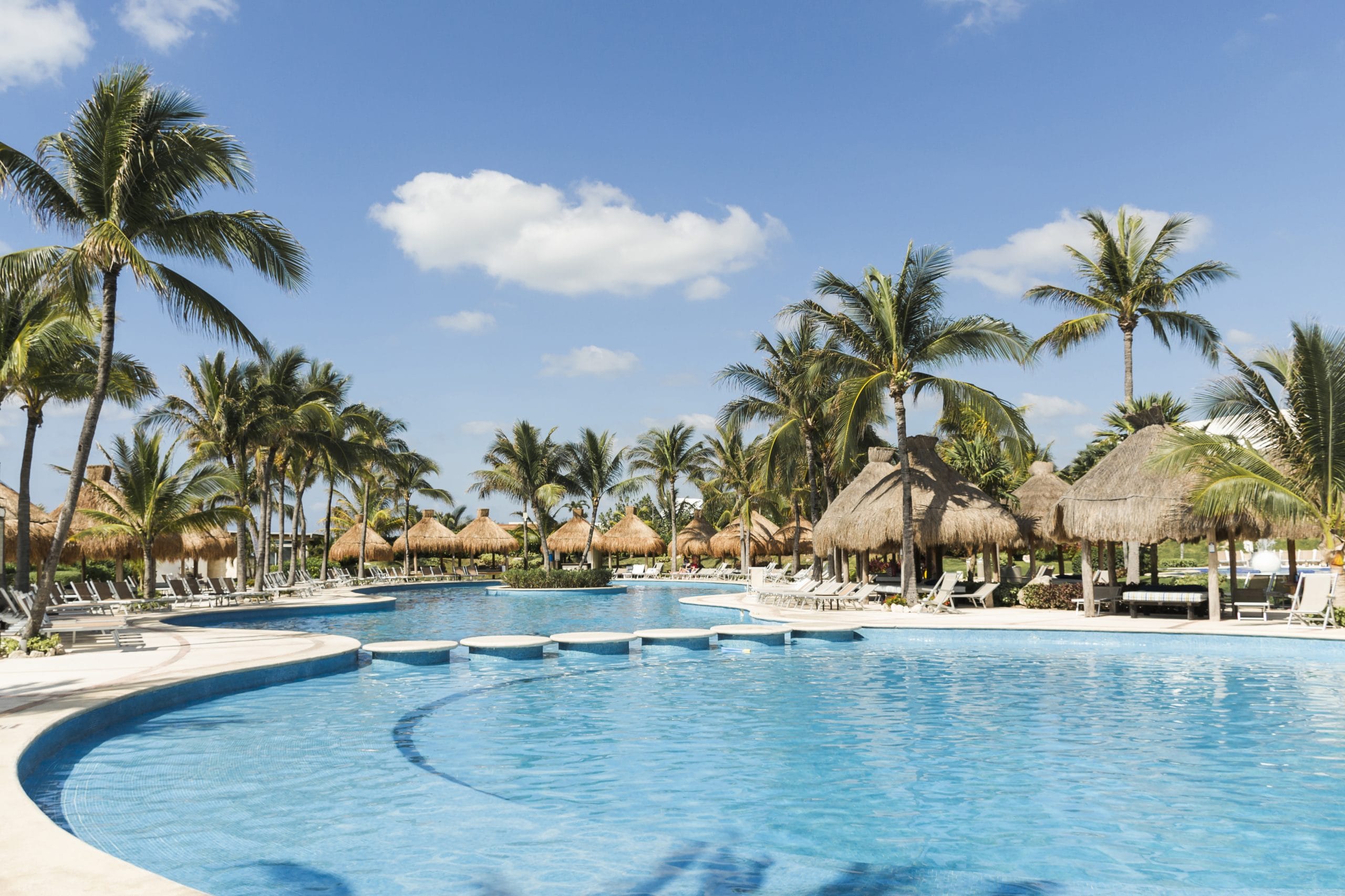 sun-loungers-near-palms-swimming-pool-sunny-day